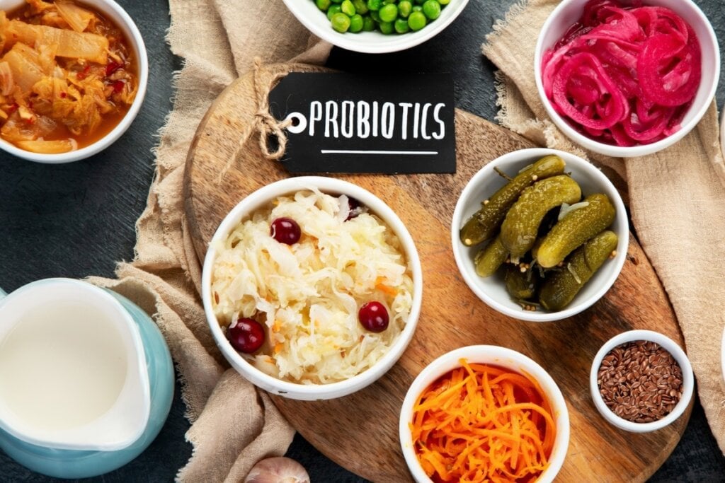 Alimentos ricos em probióticos em cima de uma tábua de madeira com uma lousa escrito "probiotics"