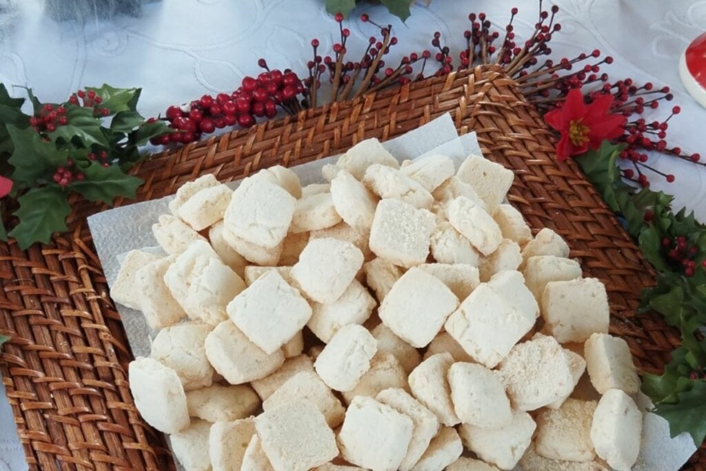 Broas de coco em cima de um prato branco decorado com flores natalinas