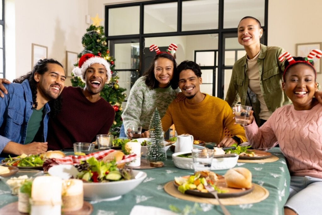 Pessoas sorrindo e felizes reunidas ao redor de uma mesa de Natal