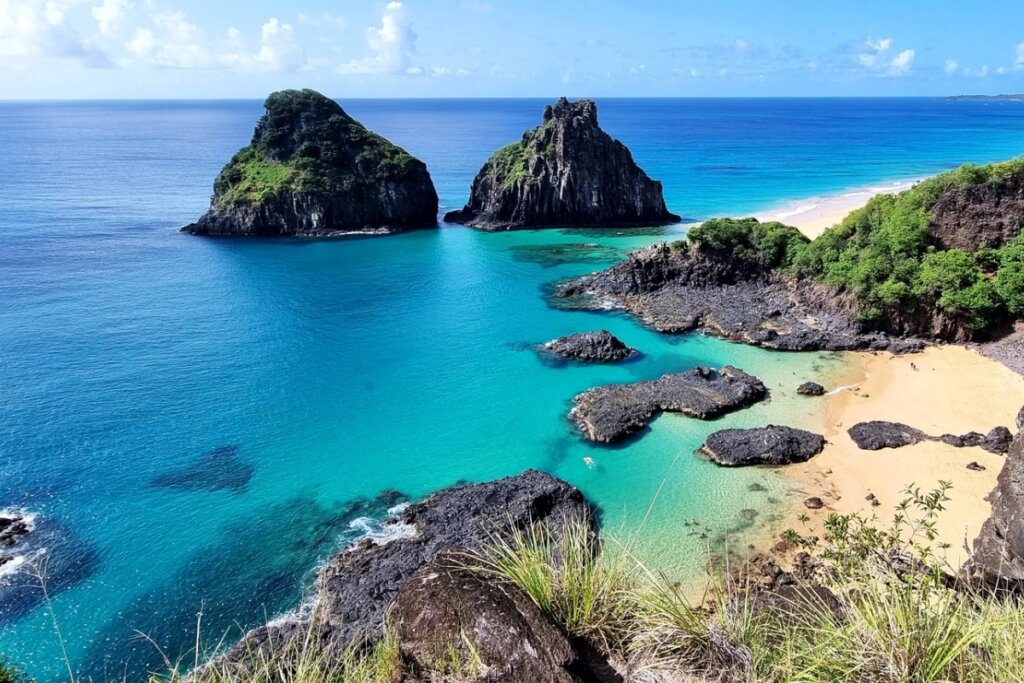 Vista aérea de uma praia em Fernando de Noronha com água azul e pequenas ilhas