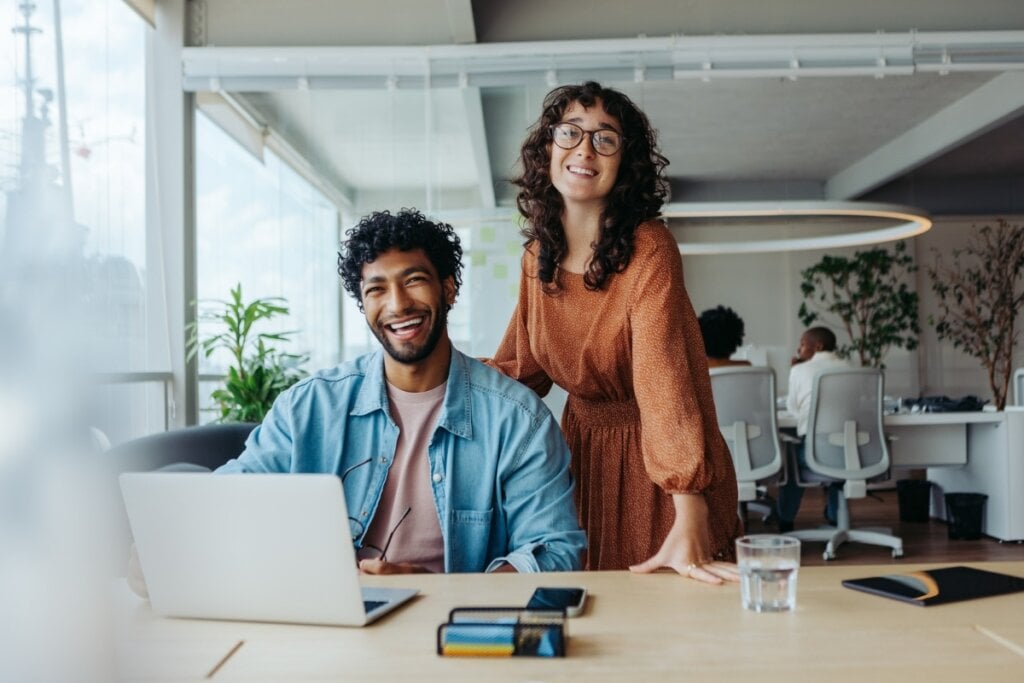 Homem e mulher em um escritório posando para foto sorrindo