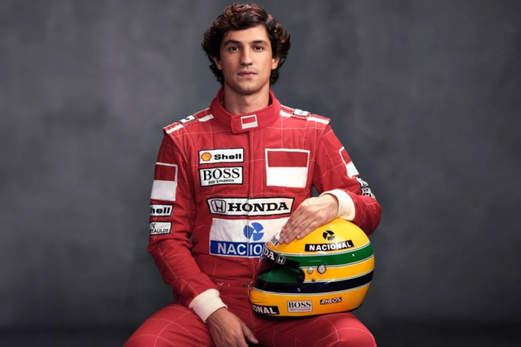 Ator interpretando Ayrton Senna com uniforme de piloto e segurando seu capacete