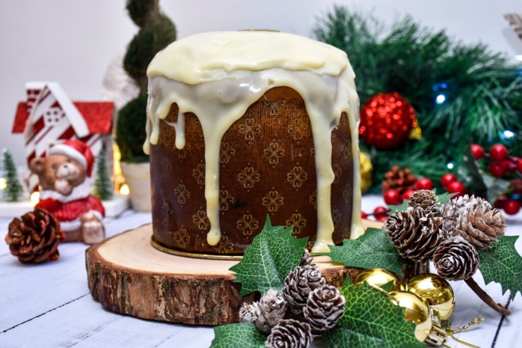 imagem de panetone com cobertura de chocolate branco e enfeites de natal em volta