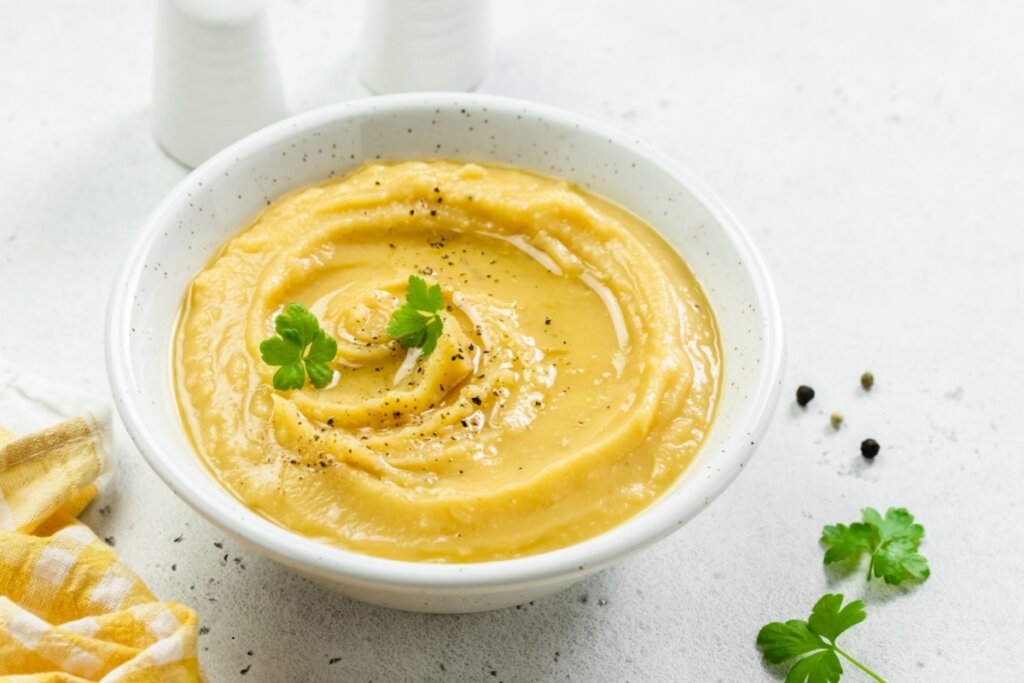 sopa de abóbora em pote branco sob superfície branca