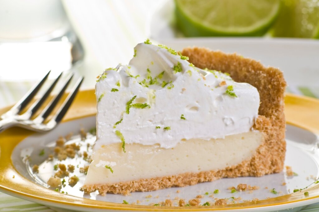 Pedaço de torta de limão servido em prato branco e amarelo