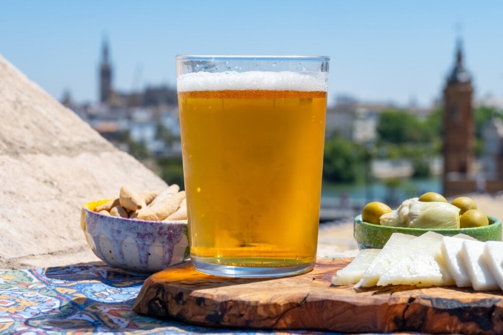 Copo de vidro com cerveja em uma mesa ao ar livre com petiscos