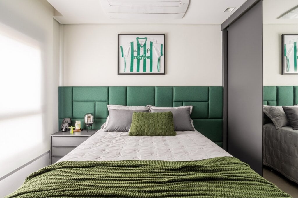 Quarto branco com cabeceira de cama verde, quadro com detalhes em verde e forro de cama verde