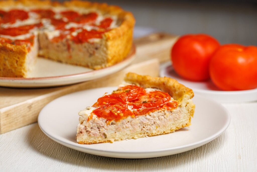 Pedaço de quiche de atum decorado com rodelas de tomate