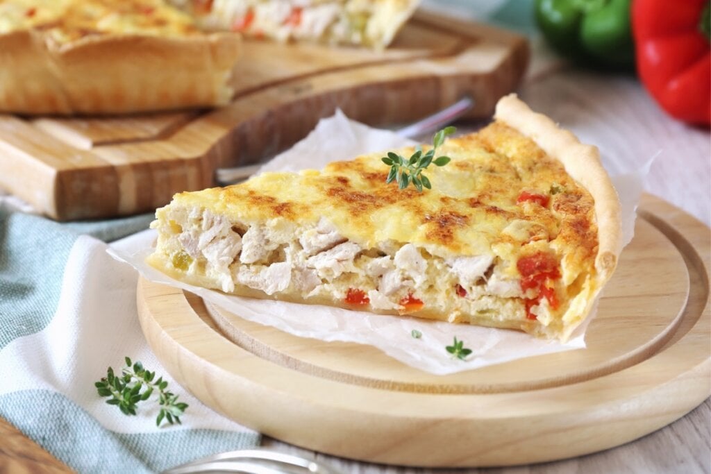 Pedaço de quiche de frango com palmito em uma tábua de madeira