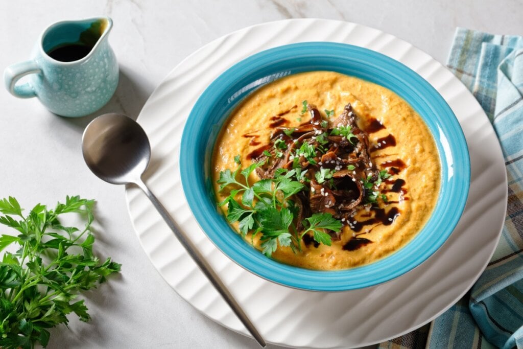 Sopa de abóbora com caldo de cogumelos e leite de coco em recipiente azul