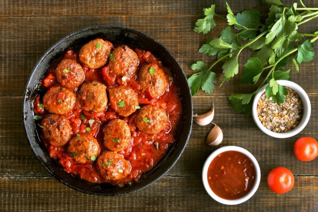 prato preto com almôndegas ao molho de tomate e ramo de salsinha ao lado