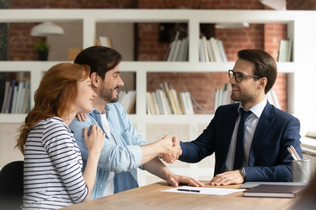 Um consultor de crédito apertando a mão de um casal satisfeito em um ambiente profissional