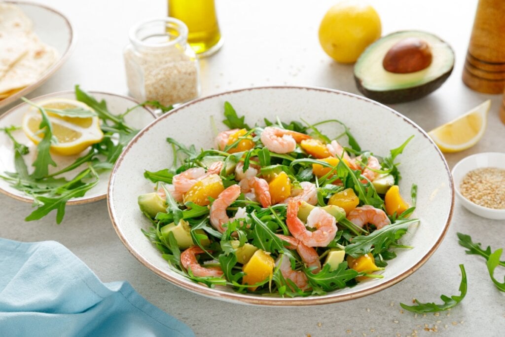 prato branco com salada de rúcula, camarão, manga e abacate